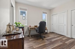 Room featuring wood-finish flooring, two windows with blinds, and white sliding closet doors - 