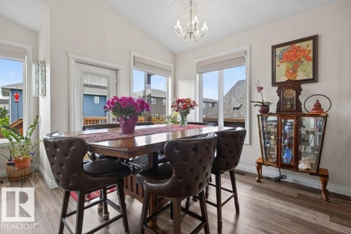 Bright dining space featuring wood-finish flooring, a vaulted ceiling, and a crystal chandelier - 71 Ratelle Circle, St. Albert, AB 