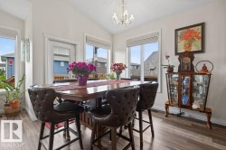Bright dining space featuring wood-finish flooring, a vaulted ceiling, and a crystal chandelier - 
