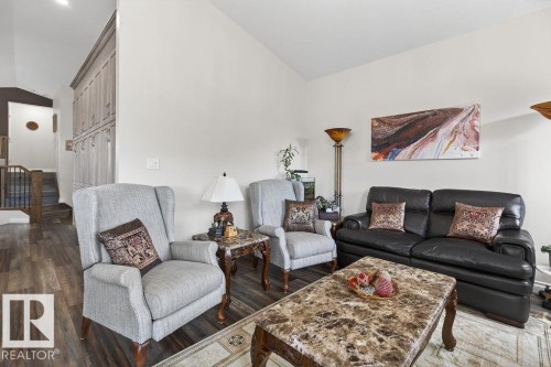 Open-concept living space featuring wood-finish flooring, vaulted ceilings, and a built-in storage wall - 71 Ratelle Circle, St. Albert, AB 