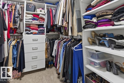 Custom closet system featuring multiple hanging rods, integrated shelving, and a central dresser unit with five drawers - 71 Ratelle Circle, St. Albert, AB 
