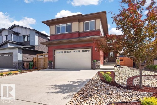Contemporary two-story residence featuring a two-car garage, red horizontal siding, and a contrasting beige upper facade - 71 Ratelle Circle, St. Albert, AB 