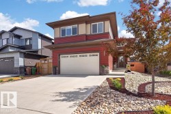 Contemporary two-story residence featuring a two-car garage, red horizontal siding, and a contrasting beige upper facade - 