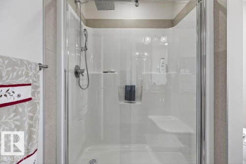 Shower enclosure with a rainfall showerhead, handheld shower fixture, integrated seating, and tiled surround - 71 Ratelle Circle, St. Albert, AB 