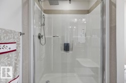 Shower enclosure with a rainfall showerhead, handheld shower fixture, integrated seating, and tiled surround - 