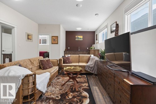 Open-concept living area featuring wood-finish flooring and a built-in wet bar with a dark countertop - 71 Ratelle Circle, St. Albert, AB 