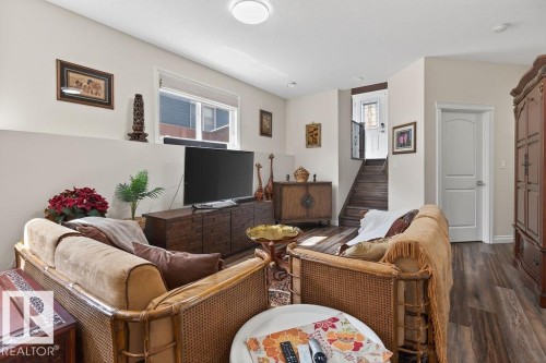 Spacious living area featuring wood-finish flooring, a contemporary ceiling light fixture, and a white interior door with paneling - 71 Ratelle Circle, St. Albert, AB 