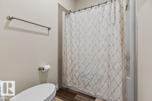 Shower stall featuring a white shower base and tile surround, complemented by wood-finish flooring - 71 Ratelle Circle, St. Albert, AB 