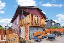 Rear exterior featuring a spacious elevated wood-finish deck with stairs leading to a concrete patio - 