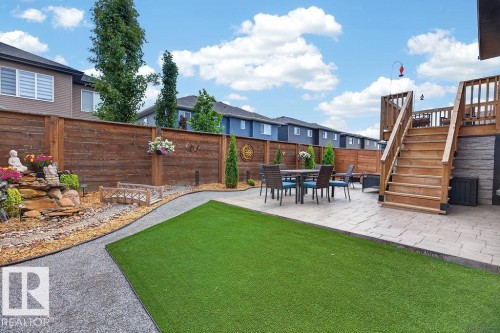 Expansive backyard featuring a multi-level wood deck, paver patio, artificial turf area, and a decorative water feature with a wooden bridge accent - 71 Ratelle Circle, St. Albert, AB 