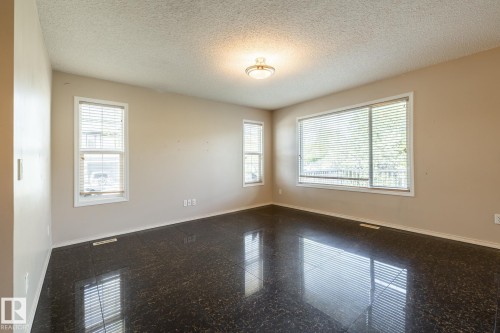 Spacious room featuring dark-toned polished tile flooring, neutral wall paint, and multiple windows with blinds - 55 Lamplight Cove, Spruce Grove, AB - Indoor Photo Showing Other Room