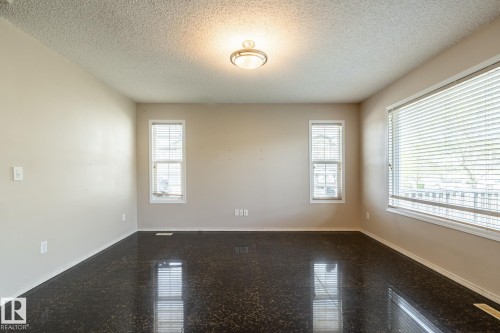 Spacious room featuring dark-toned flooring, light neutral-toned walls, and a textured ceiling - 55 Lamplight Cove, Spruce Grove, AB - Indoor Photo Showing Other Room