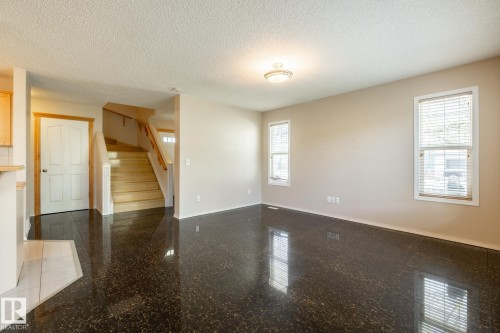 Spacious living area featuring dark, reflective flooring, light neutral wall paint, and white trim windows - 55 Lamplight Cove, Spruce Grove, AB - Indoor Photo Showing Other Room
