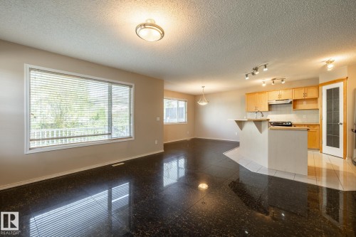 Open-concept living area featuring dark polished tile flooring and a large window with blinds - 55 Lamplight Cove, Spruce Grove, AB - Indoor Photo Showing Kitchen