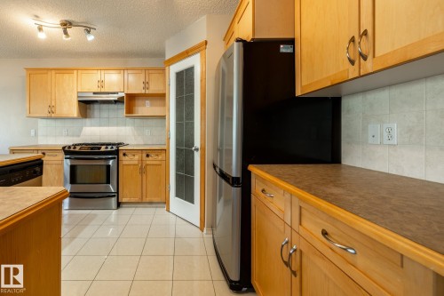 Kitchen featuring light wood cabinetry, white tile flooring, stainless steel range, and a two-door refrigerator - 55 Lamplight Cove, Spruce Grove, AB - Indoor Photo Showing Kitchen With Stainless Steel Kitchen