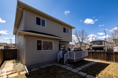 Rear exterior featuring light-toned horizontal siding, a private wood fence, and a white deck with railings and steps - 55 Lamplight Cove, Spruce Grove, AB - Outdoor With Exterior