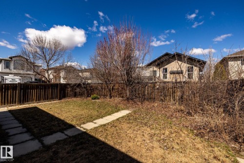 Expansive backyard featuring a partial concrete patio, a concrete walkway, and a wood fence - 55 Lamplight Cove, Spruce Grove, AB - Outdoor