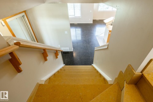 Staircase with light wood-finish treads and handrail, featuring white risers and a contrasting dark tile floor visible at the bottom - 55 Lamplight Cove, Spruce Grove, AB - Indoor Photo Showing Other Room