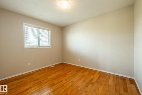 Interior room featuring wood-finish flooring, neutral wall tones, and a window with horizontal blinds - 55 Lamplight Cove, Spruce Grove, AB - Indoor Photo Showing Other Room