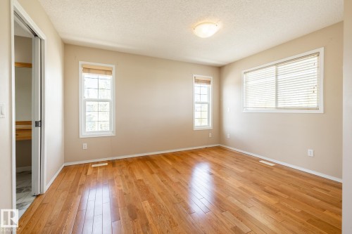 Spacious room featuring rich wood-finish flooring, neutral wall tones, and two distinct windows providing natural light - 55 Lamplight Cove, Spruce Grove, AB - Indoor Photo Showing Other Room