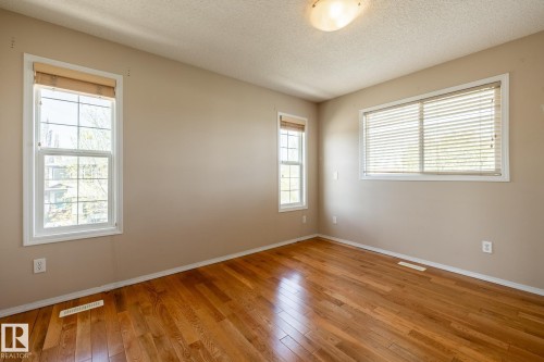 Wood-finish flooring throughout, complemented by neutral wall tones - 55 Lamplight Cove, Spruce Grove, AB - Indoor Photo Showing Other Room