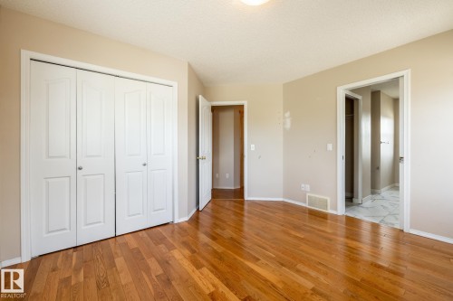 Warm wood-finish flooring complements the neutral wall palette - 55 Lamplight Cove, Spruce Grove, AB - Indoor Photo Showing Other Room