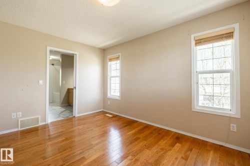 Spacious room with wood-finish flooring, two large windows with horizontal blinds, and neutral wall paint - 55 Lamplight Cove, Spruce Grove, AB - Indoor Photo Showing Other Room