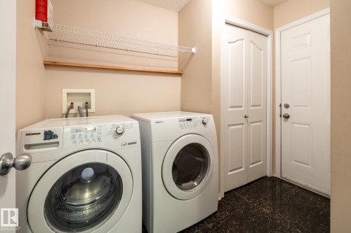 Dedicated laundry space featuring a wire shelving unit, wood shelf, and dark-toned flooring - 55 Lamplight Cove, Spruce Grove, AB - Indoor Photo Showing Laundry Room