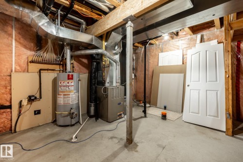 Unfinished basement space featuring a hot water heater, furnace, exposed wood joists, structural support beams, and concrete flooring - 55 Lamplight Cove, Spruce Grove, AB - Indoor Photo Showing Basement
