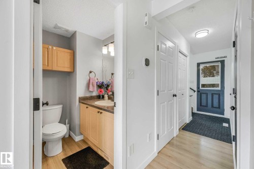 Powder room featuring a wood-finish vanity with a countertop, an undermount sink, and a mirrored wall - 2921 23 Street, Edmonton, AB 