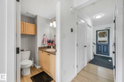 Powder room featuring a wood-finish vanity with a countertop, an undermount sink, and a mirrored wall - 