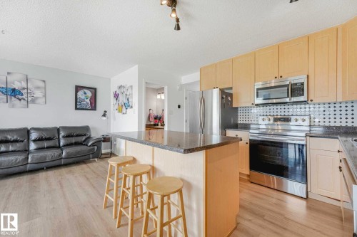 Kitchen island with a dark countertop and three-track lighting fixtures - 2921 23 Street, Edmonton, AB 