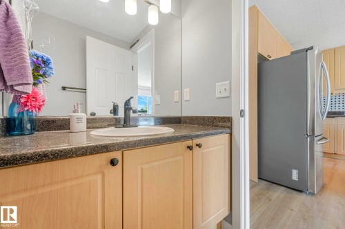 Bathroom vanity featuring a granite-look countertop, integrated sink, and light wood cabinetry - 2921 23 Street, Edmonton, AB 