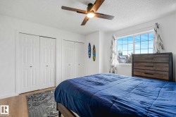 Bedroom featuring light wood-finish flooring, a ceiling fan with integrated lighting, white bi-fold closet doors, and a large window - 