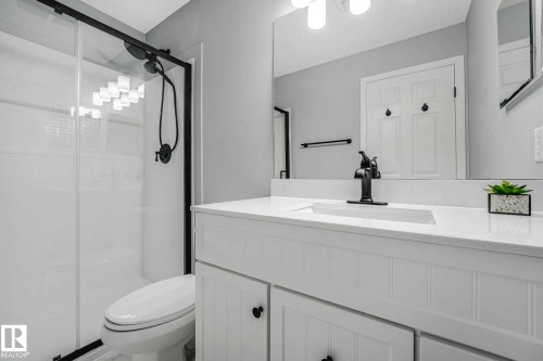Modern bathroom featuring a white vanity with panel-front cabinetry, a single basin sink, and a matte black faucet - 2921 23 Street, Edmonton, AB 