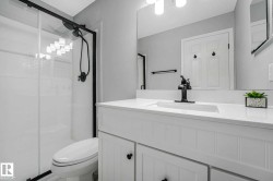 Modern bathroom featuring a white vanity with panel-front cabinetry, a single basin sink, and a matte black faucet - 