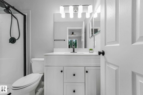 Bathroom featuring a single-sink vanity with white cabinetry, a built-in mirror, and contemporary lighting - 2921 23 Street, Edmonton, AB 