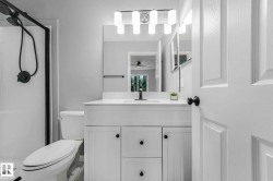 Bathroom featuring a single-sink vanity with white cabinetry, a built-in mirror, and contemporary lighting - 