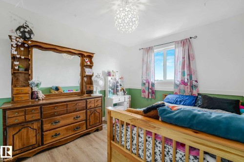 Room featuring wood-finish flooring, a wall-mounted light fixture, and a light-colored window frame - 2921 23 Street, Edmonton, AB 