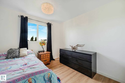 Bedroom featuring wood-finish flooring, a double-pane window, and a ceiling-mounted light fixture - 2921 23 Street, Edmonton, AB 