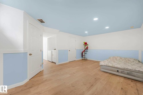 Spacious room featuring wood-finish flooring, recessed lighting, and a light blue ceiling - 2921 23 Street, Edmonton, AB 