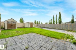 Expansive backyard featuring a combination of paver patio and lawn areas - 