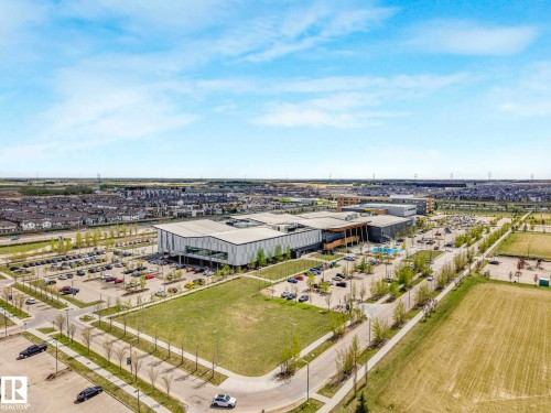 Expansive contemporary building with multiple entrances, extensive parking facilities, surrounding green spaces, and a nearby residential development - 2921 23 Street, Edmonton, AB 