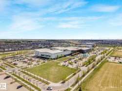 Expansive contemporary building with multiple entrances, extensive parking facilities, surrounding green spaces, and a nearby residential development - 