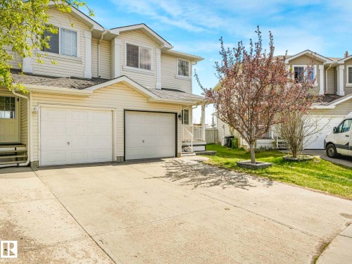 Exterior featuring light-toned horizontal siding, a gabled roofline, and a concrete driveway - 2921 23 Street, Edmonton, AB 