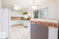 Kitchen featuring white cabinetry, tile flooring, tile backsplash, and a sliding glass door - 