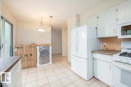 Kitchen featuring white cabinetry, white appliances, tile flooring, and a tile backsplash - 4107 147 Street, Edmonton, AB 