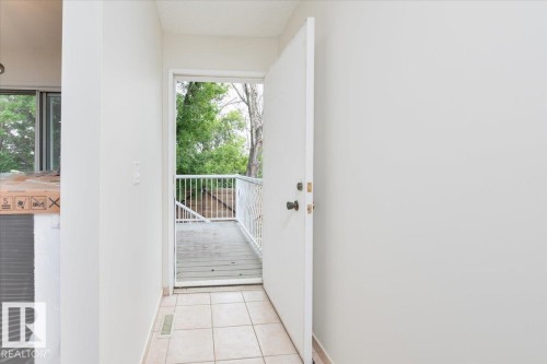 Entranceway featuring light-toned tile flooring, white walls, and a white door opening to an outdoor deck - 4107 147 Street, Edmonton, AB 