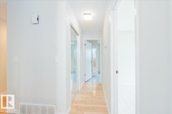 Hallway featuring wood-finish flooring, white walls, and a ceiling-mounted light fixture - 
