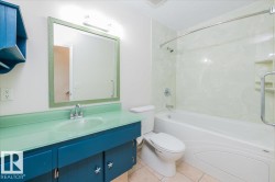Bathroom featuring a glass countertop vanity with an integrated basin, a framed mirror, and a tub-shower combination with a textured surround - 